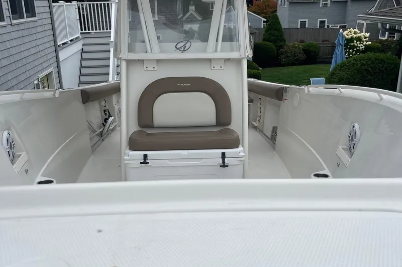 Slide: The Image of 2013 Sailfish 270 CC boat interior with seating and console, docked near residential area. - 18