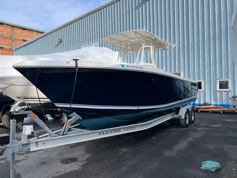 Slide: The Image of 2013 Sailfish 270 CC boat on trailer, parked near a corrugated metal building. - 3