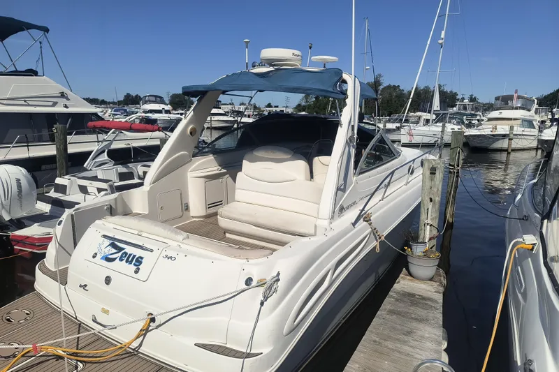 The Image of 2000 Sea Ray 340 Sundancer docked at marina, featuring spacious seating and sleek design. - 3