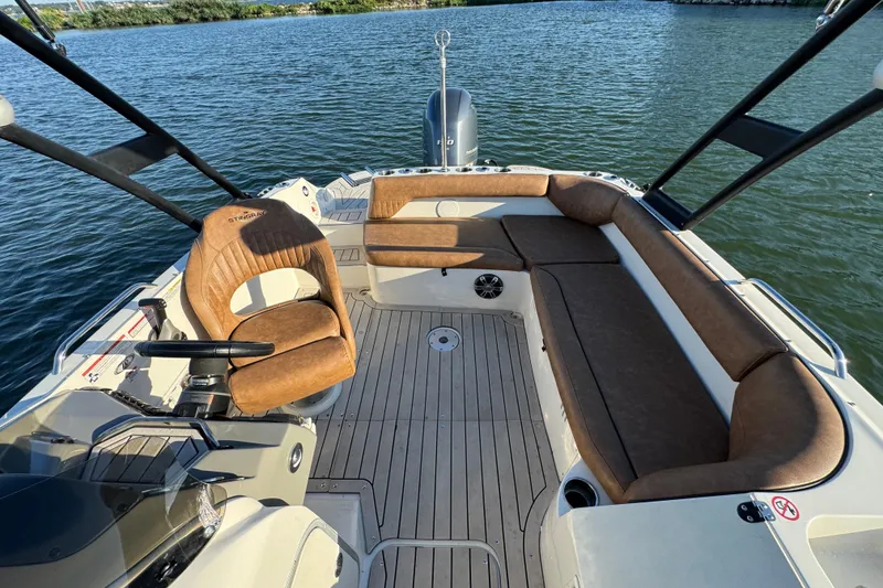 Slide: The Image of 2021 Stingray 192 SC boat interior with brown seating and steering wheel on water. - 14