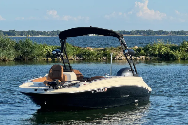 Slide: The Image of 2021 Stingray 192 SC boat on a serene lake with lush greenery. - 2