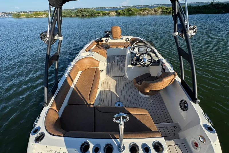 Slide: The Image of 2021 Stingray 192 SC boat interior with brown seating, steering wheel, and water view. - 21