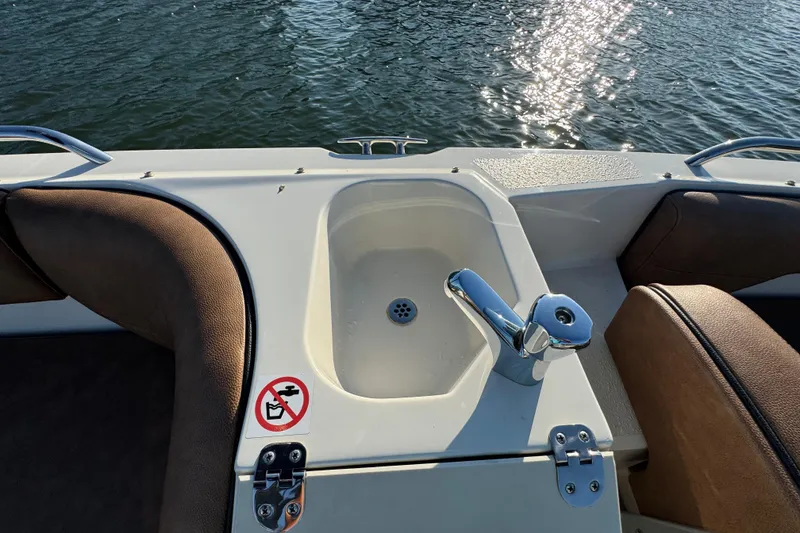 Slide: The Image of 2021 Stingray 192 SC boat interior with sink and seating, on a sunny day. - 24