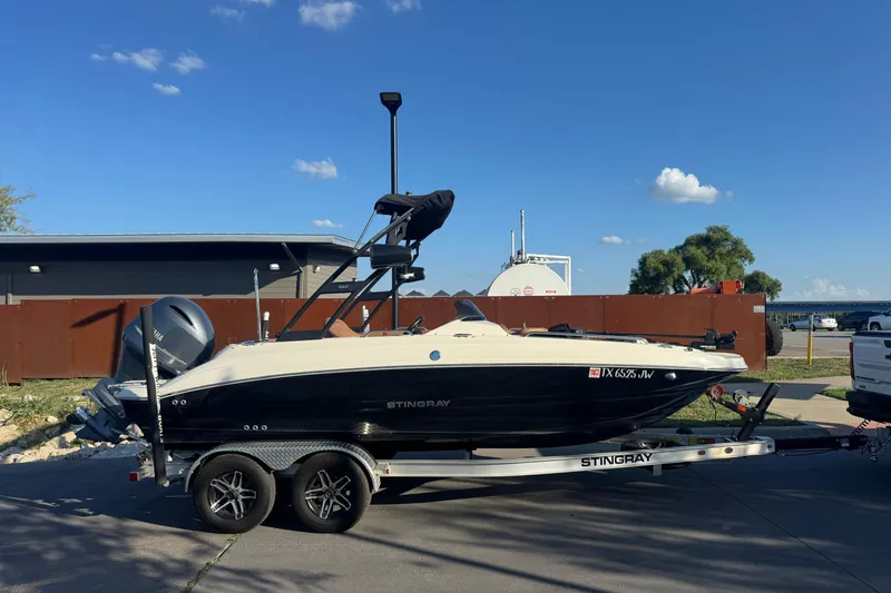 Slide: The Image of 2021 Stingray 192 SC boat on trailer, parked outdoors under clear blue sky. - 6