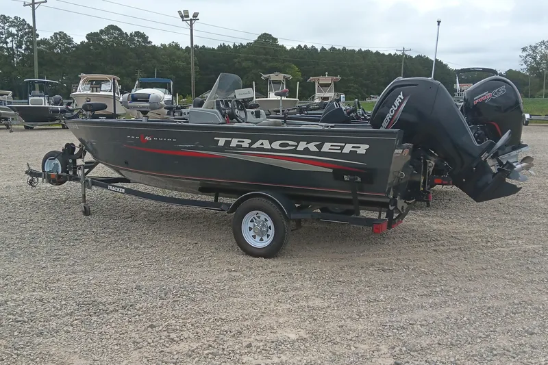 The Image of 2019 Tracker Pro Guide V-16 SC boat on trailer, parked in a gravel lot. - 0