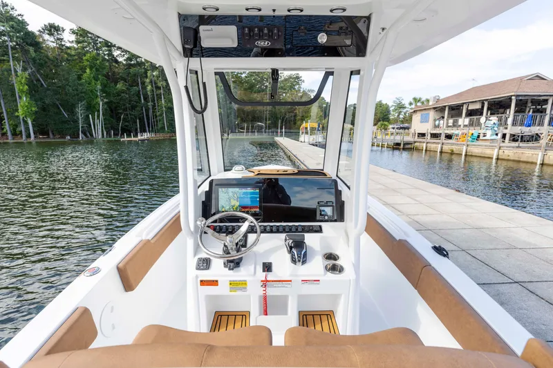 Slide: The Image of 2026 Sea Hunt Ultra 235 SE boat interior with modern dashboard and scenic marina view. - 11