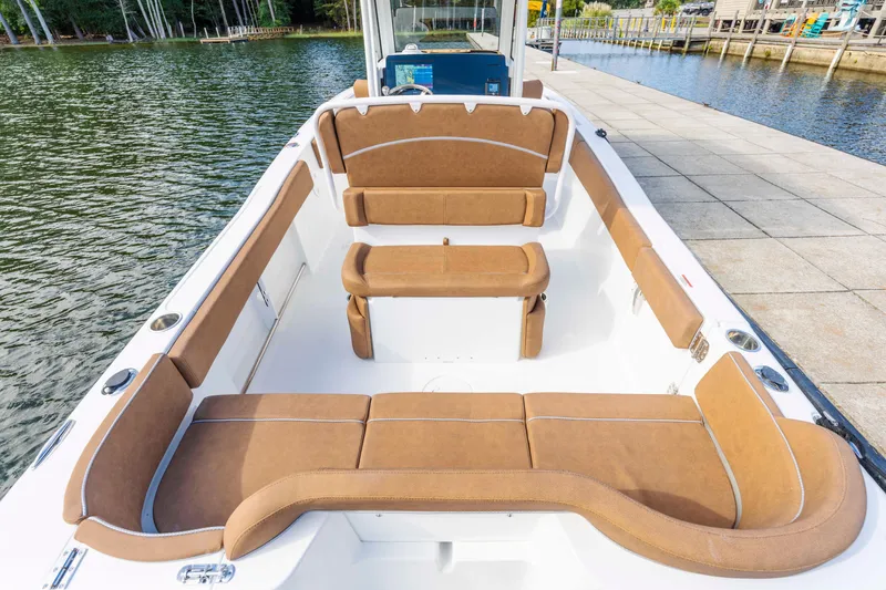 Slide: The Image of 2026 Sea Hunt Ultra 235 SE boat interior with tan seating, docked by the water. - 12