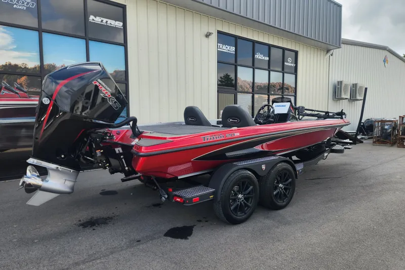 Slide: The Image of 2025 Triton 20XP Patriot boat, red and black, parked outside a dealership. - 2