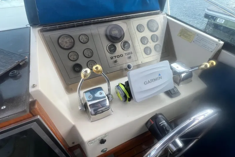 Slide: The Image of 1984 Tiara 2700 boat dashboard with Garmin device and control levers. - 10