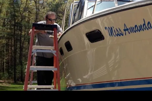 Slide: The Image of Man working on 1984 Tiara 2700 boat named "Miss Amanda" using a ladder. - 5