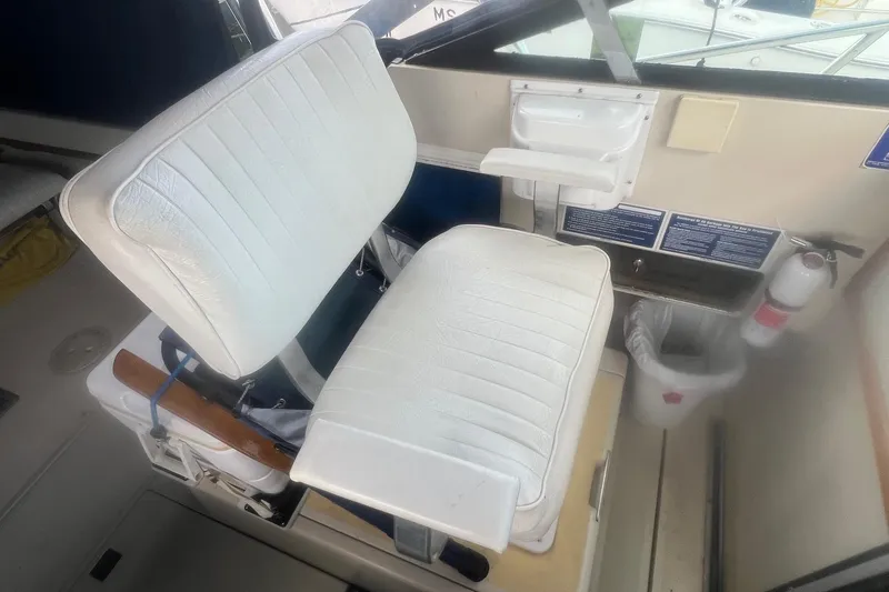 Slide: The Image of Captain's chair on a 1984 Tiara 2700 boat, featuring white upholstery and cockpit controls. - 9