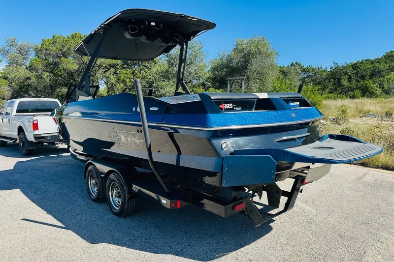 Slide: The Image of 2014 Axis A24 boat on trailer, parked outdoors with trees in background. - 10