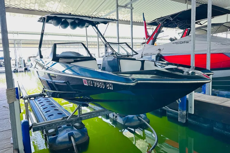 Slide: The Image of 2014 Axis A24 boat on lift in marina, sleek design, ready for water activities. - 11