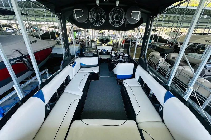 Slide: The Image of 2014 Axis A24 boat interior with spacious seating and modern dashboard in a marina. - 14