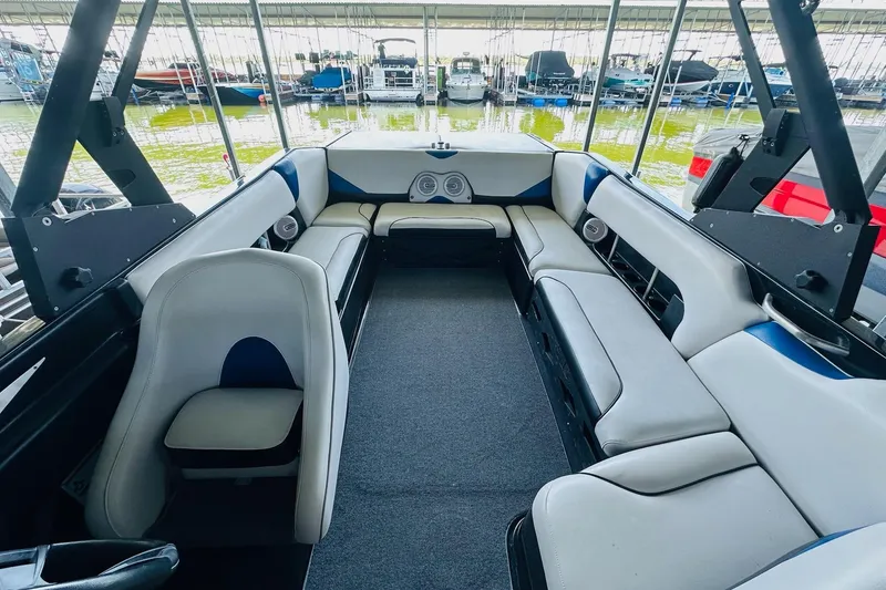 Slide: The Image of 2014 Axis A24 boat interior with spacious seating and modern design in a marina setting. - 16