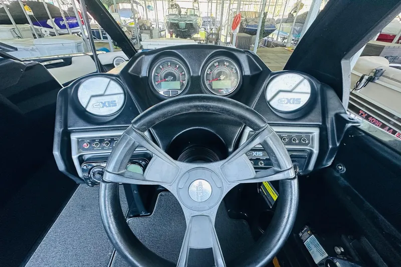 Slide: The Image of 2014 Axis A24 boat dashboard with steering wheel and gauges in a marina setting. - 17
