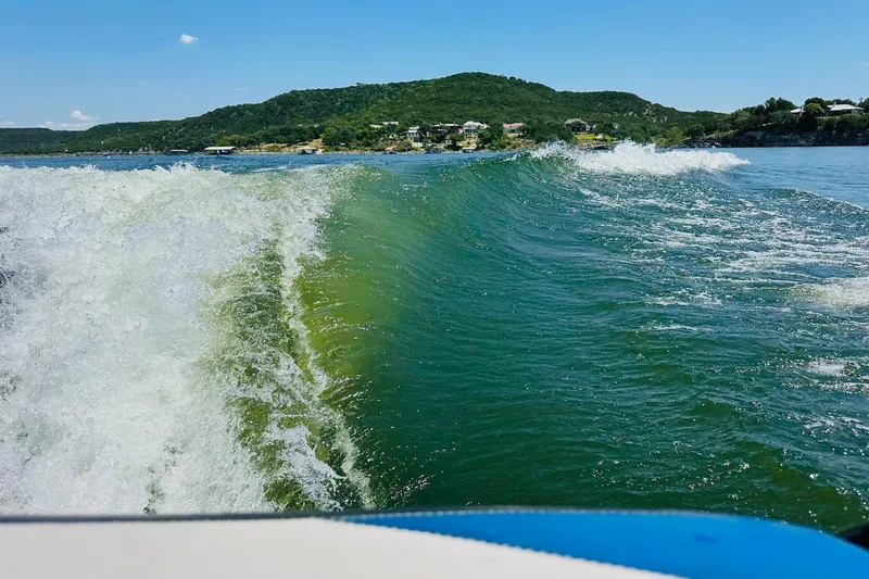 Slide: The Image of Wake created by 2014 Axis A24 boat on a sunny lake with hills in background. - 23