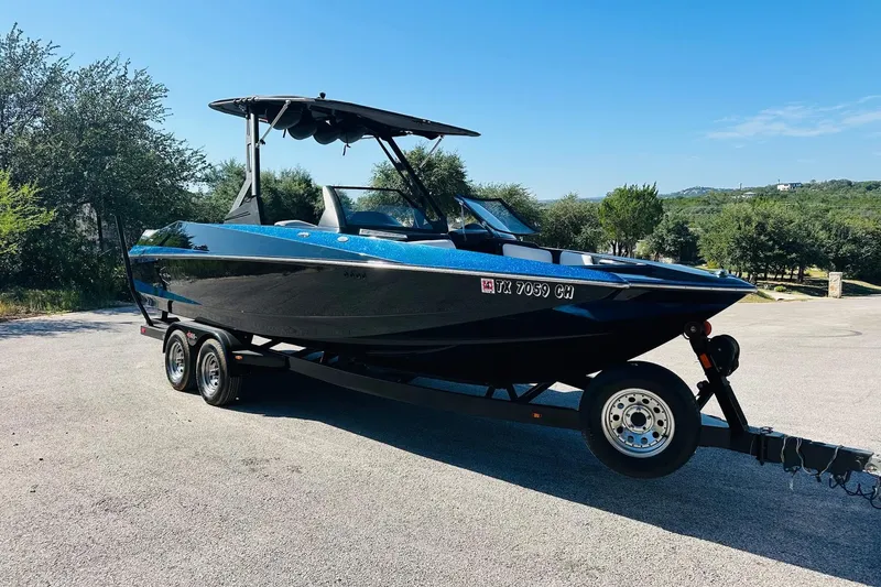 Slide: The Image of 2014 Axis A24 boat on trailer, parked outdoors under clear blue sky. - 6