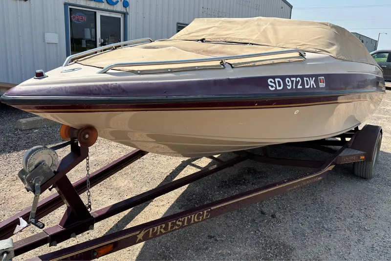 Slide: The Image of 2001 Crownline 18' boat on trailer, covered, parked outside a building. - 7