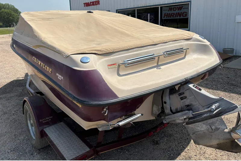 Slide: The Image of 2001 Crownline 18' boat with cover on trailer, parked outside a building. - 8
