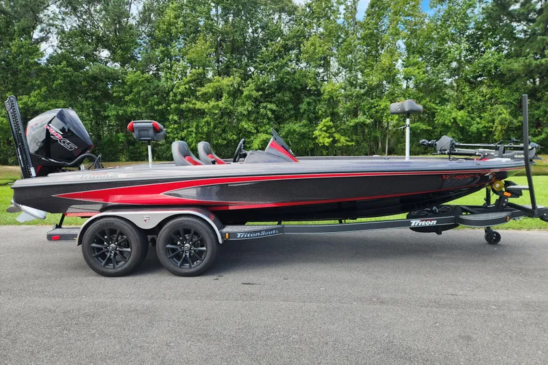 The Image of 2025 Triton 21XP Patriot boat on trailer, parked on road with lush green background. - 0