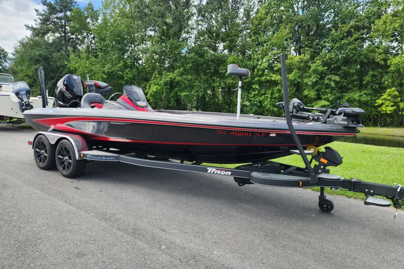 Slide: The Image of 2025 Triton 21XP Patriot boat on trailer, parked on road with lush green background. - 1