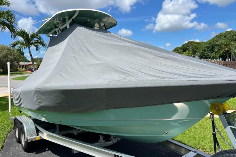 Slide: The Image of 2024 Sea Hunt BX 22 BR boat covered on trailer, parked outdoors under blue sky. - 11