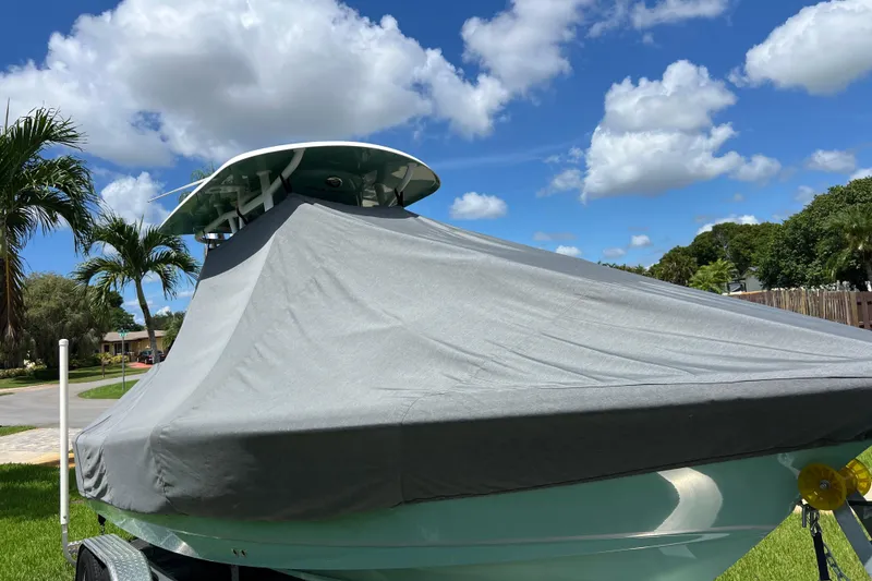 Slide: The Image of 2024 Sea Hunt BX 22 BR boat covered, parked outdoors under a clear blue sky. - 12