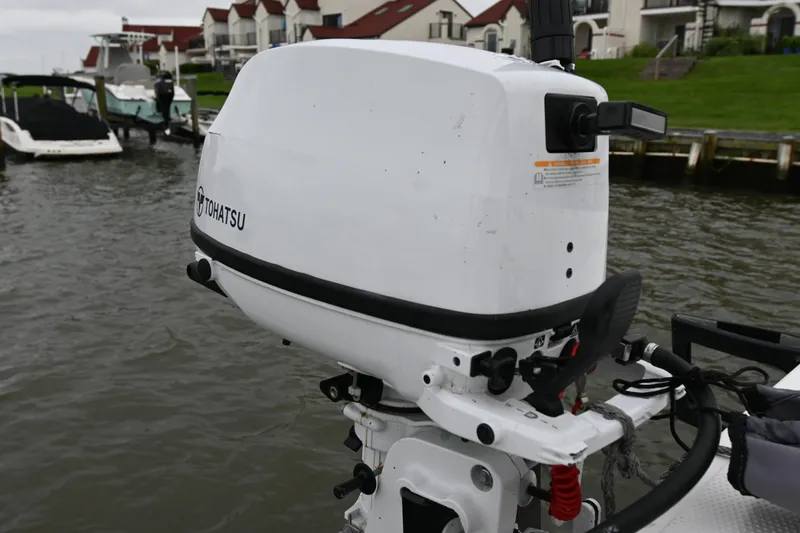 Slide: The Image of Tohatsu outboard motor on a 2022 Beneteau First 24 sailboat, docked by waterfront homes. - 18