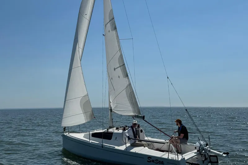 Slide: The Image of 2022 Beneteau First 24 sailboat on open water, two people onboard, clear sky. - 3