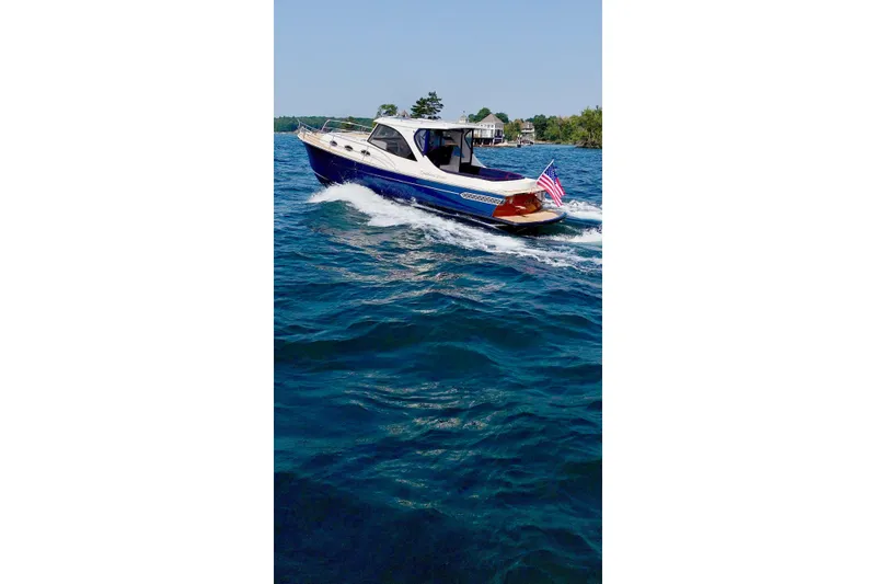 Slide: The Image of 2024 DaVinci 30HT boat cruising on blue water with American flag. - 0