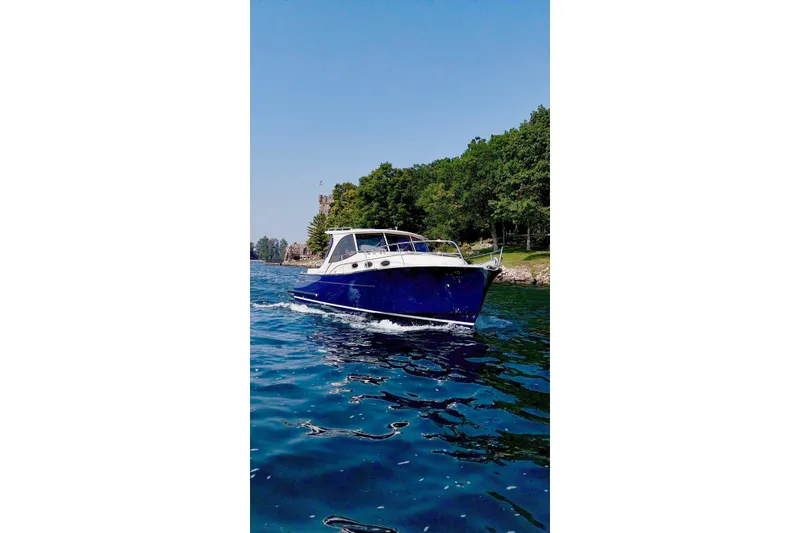Slide: The Image of 2024 DaVinci 30HT boat cruising on a scenic lake with lush greenery. - 1