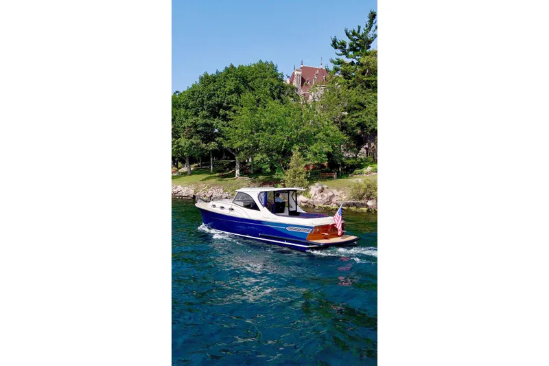 Slide: The Image of 2024 DaVinci 30HT boat cruising on a scenic lake with lush greenery. - 3