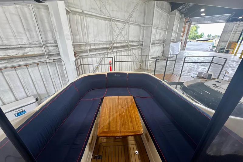 Slide: The Image of Interior of 2024 DaVinci 30HT boat with blue seating and wooden table in a warehouse. - 35