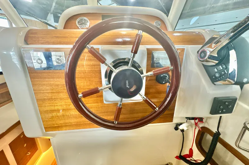 Slide: The Image of 2024 DaVinci 30HT boat steering wheel with wood accents and control panel. - 39
