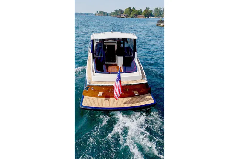 Slide: The Image of 2024 DaVinci 30HT yacht cruising on blue water, rear view with American flag. - 4