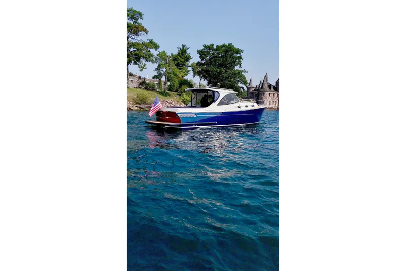 Slide: The Image of 2024 DaVinci 30HT boat on blue water, near shoreline with trees and buildings. - 5