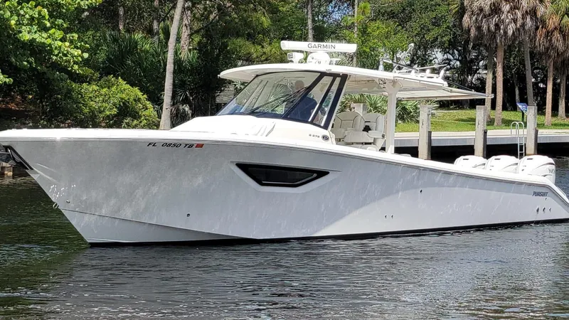 Slide: The Image of 2021 Pursuit S 378 Sport boat on a calm waterway, surrounded by lush greenery. - 0