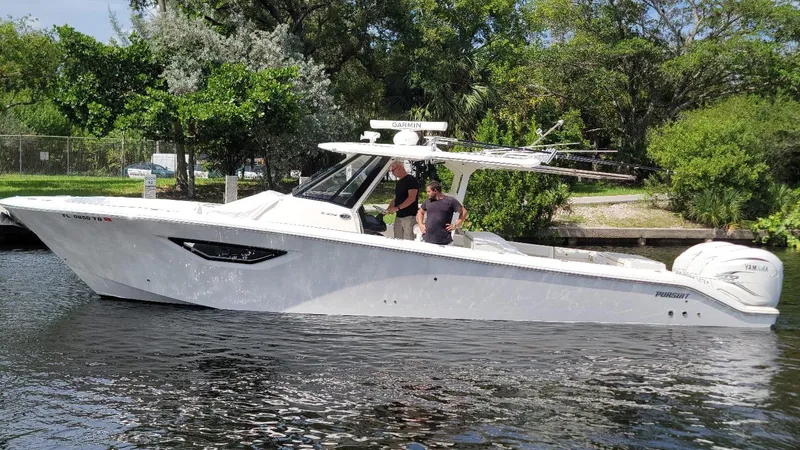 Slide: The Image of 2021 Pursuit S 378 Sport boat on a calm river, surrounded by lush greenery. - 11