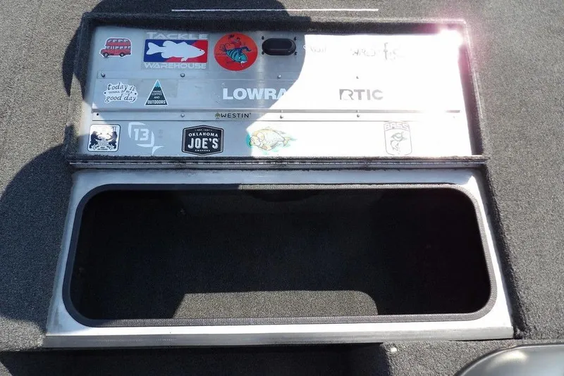Slide: The Image of 2013 Lowe Stinger ST175 boat storage compartment with various stickers and logos. - 28