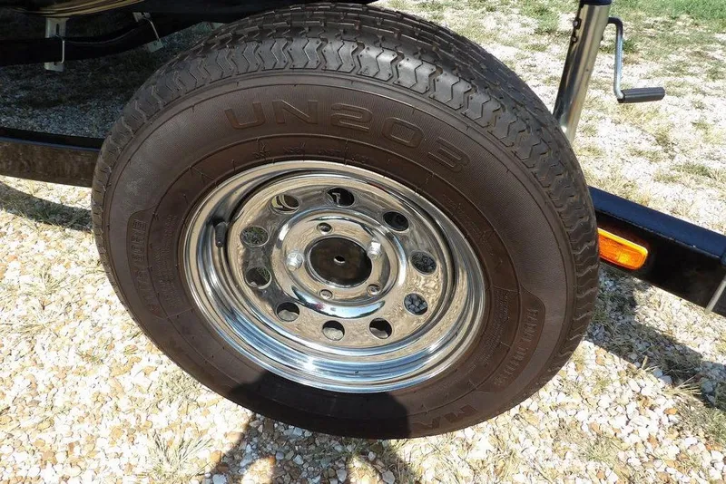 Slide: The Image of 2013 Lowe Stinger ST175 trailer tire with chrome rim on gravel surface. - 39