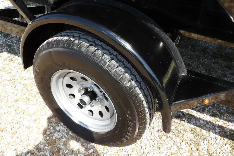 Slide: The Image of 2013 Lowe Stinger ST175 trailer wheel with black fender on gravel surface. - 40