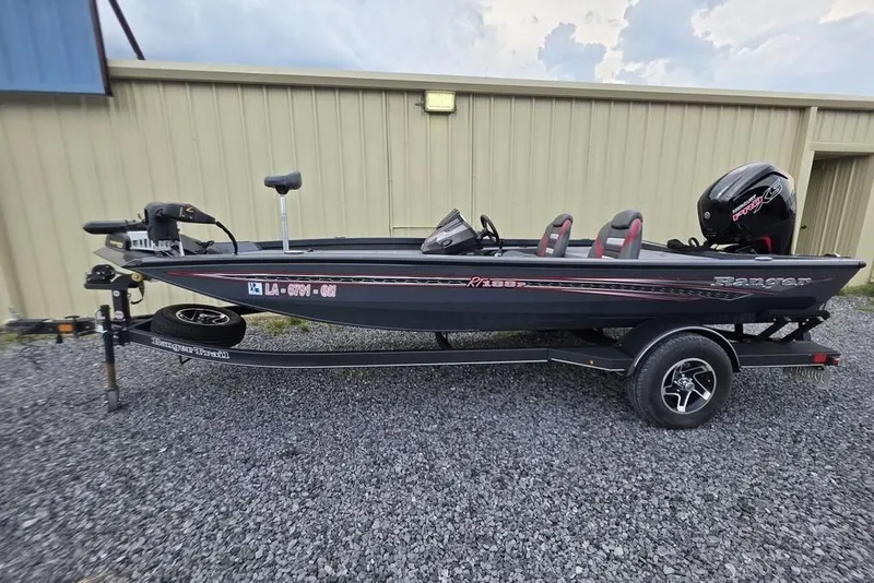 Slide: The Image of 2022 Ranger RT188P fishing boat on trailer, parked on gravel near a beige building. - 22