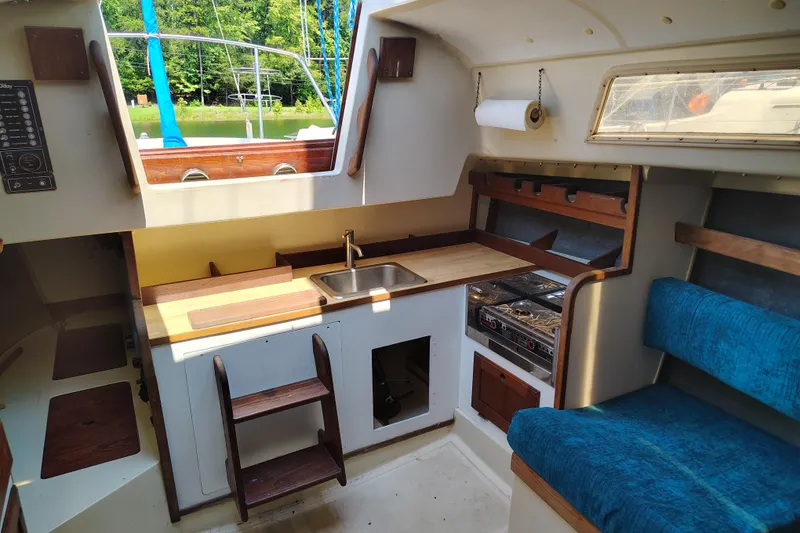 Slide: The Image of 1979 O'Day 28 sailboat interior with kitchenette, sink, stove, and blue seating. - 19