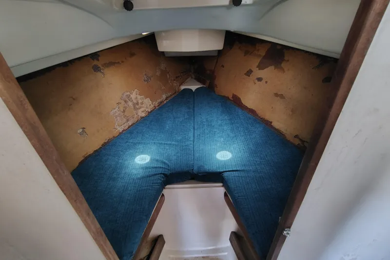Slide: The Image of 1979 O'Day 28 sailboat cabin interior with blue cushions and worn walls. - 24