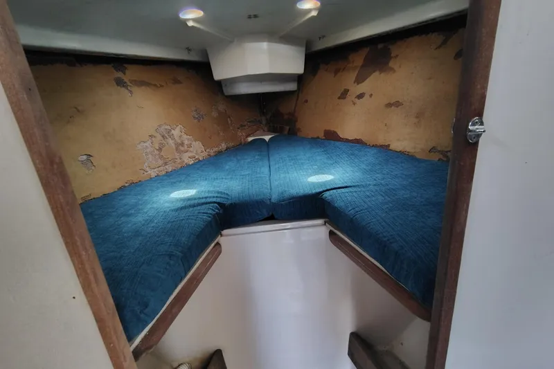 Slide: The Image of 1979 O'Day 28 sailboat cabin with blue cushions and worn interior walls. - 25