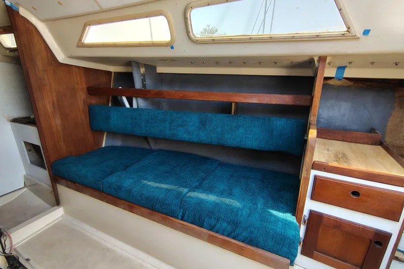 Slide: The Image of Interior of a 1979 O'Day 28 sailboat with blue cushioned seating and wooden cabinetry. - 26