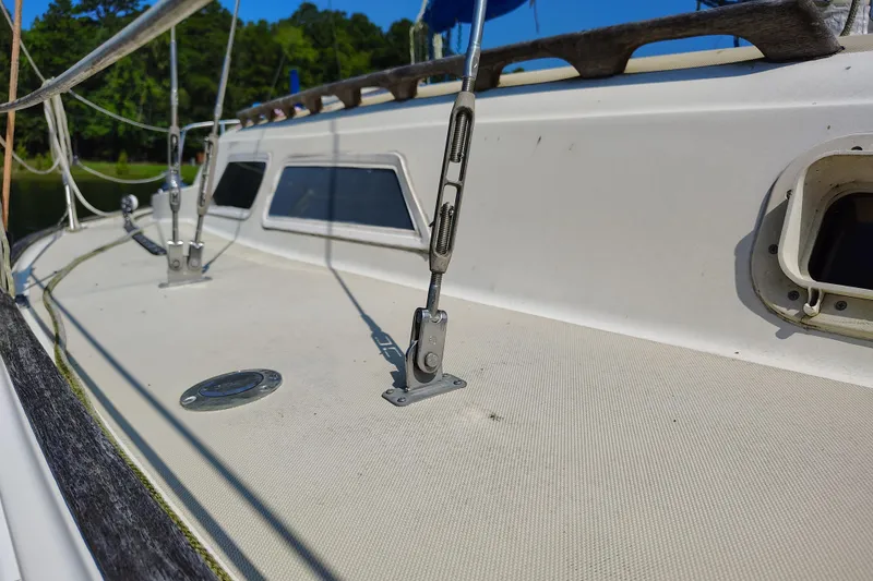 Slide: The Image of 1979 O'Day 28 sailboat deck with rigging and windows, docked near lush greenery. - 6