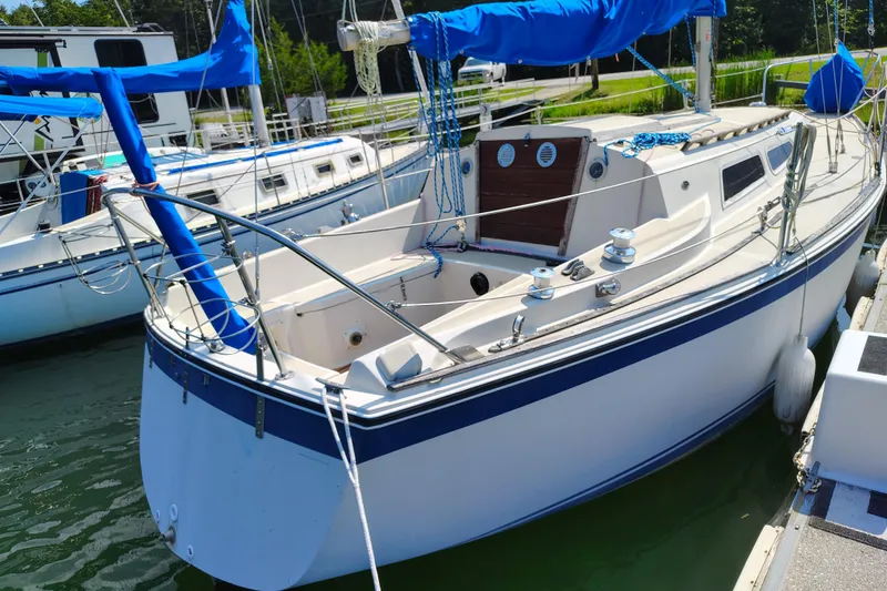 Slide: The Image of 1979 O'Day 28 sailboat docked, featuring blue accents and a spacious cockpit. - 7