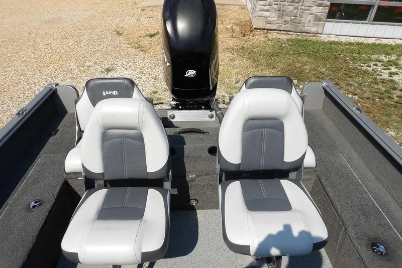 Slide: The Image of 2012 Lund 1775 Impact Sport boat interior with two gray and white seats, outboard motor visible. - 11